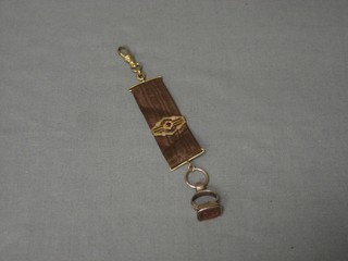 A gilt metal intaglio cut seal in the form of a gentleman, hung a brown silk ribbon