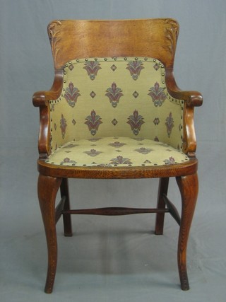 An Art Nouveau carved oak tub back armchair, raised on cabriole supports