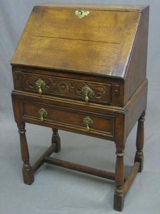An 18th Century style honey oak bureau on stand, the fall front revealing a well fitted interior above 2 long drawers, raised on turned and block supports with H framed stretcher 23"