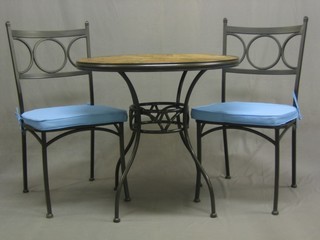 A circular iron and mosaic garden table together with 2 matching iron framed chairs
