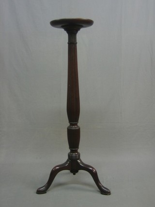A 19th Century mahogany torchere raised on a turned and fluted column 