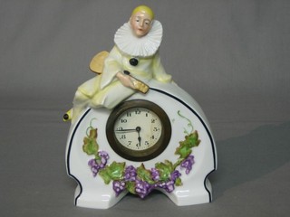An Art Deco timepiece with Arabic numerals contained in a pottery case surmounted by a figure of a Pierrot 8" (cracked)