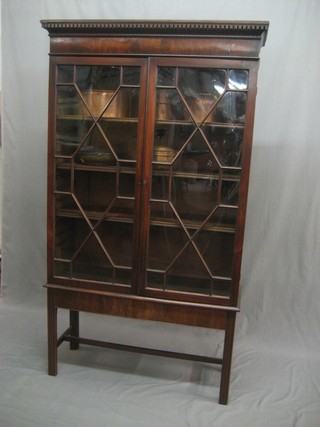 A 19th Century mahogany bookcase with moulded and dentil cornice, the interior fitted adjustable shelves enclosed by astragal glazed panelled doors, raised on a stand with square tapering supports 38"