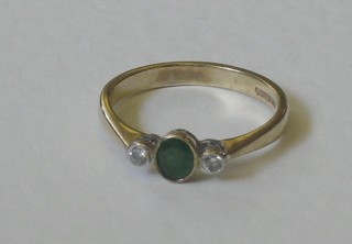 A 9ct yellow gold dress ring set an oval cut emerald supported by 2 diamonds