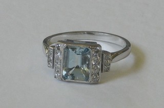 A lady's 18ct white gold dress ring set a rectangular cut aquamarine with numerous diamonds to the shoulders
