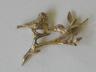 A gilt metal brooch in the form of 2 birds on a branch, the eyes set red stones