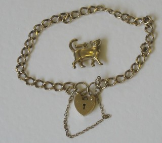 A gilt metal curb link chain with padlock clasp and a gilt metal charm in the form of a cat