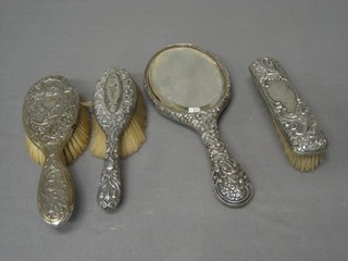 An embossed silver backed 4 piece dressing table set with hand mirror, 2 hair brushes and a clothes brush