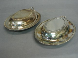 A pair of oval silver plated twin handled entree dishes and covers with gadrooned decoration