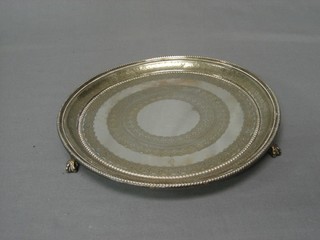 A circular silver plated salver with bead work border raised on 3 hoof supports 10"