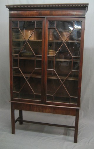 A Georgian  mahogany bookcase with moulded and dentil cornice, the interior fitted adjustable shelves enclosed by astragal glazed panelled doors, raised on a stand with square tapering supports 38"