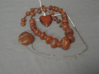 An amber coloured heart shaped pendant, 1 other and a string of beads