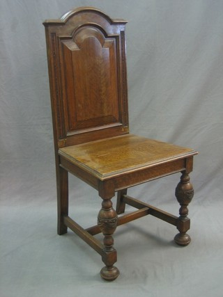 An Edwardian oak hall chair with solid seat and back, raised on turned supports with H framed stretcher