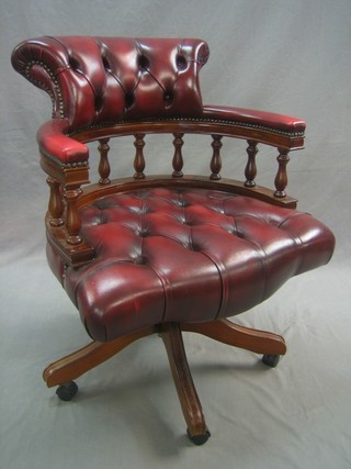 A Victorian style mahogany revolving office chair upholstered in red buttoned back leather