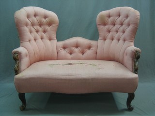 A Victorian mahogany show framed double spoon back settee upholstered in pink, raised on cabriole supports 53"