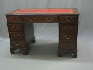 A mahogany kneehole pedestal desk with inset tooled leather writing surface, fitted 1 long and 8 short drawers, raised on bracket feet 49"