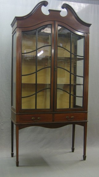 An Edwardian inlaid mahogany display cabinet with broken pediment, the interior fitted shelves enclosed by astragal glazed panelled doors, the base fitted 2 long drawers, raised on square tapering supports and ending in spade feet 36"