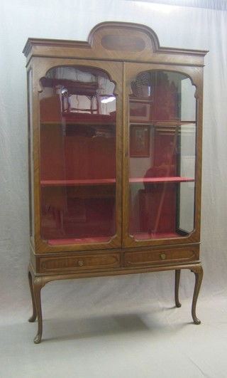 A walnut display cabinet, the interior fitted shelves enclosed by glazed panelled doors, the base fitted 2 short drawers, raised on cabriole supports 42"