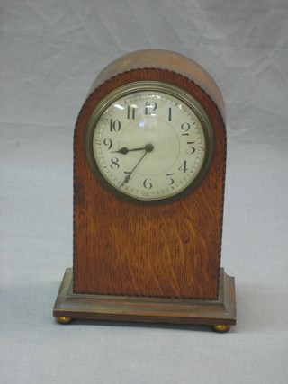 A 1930's bedroom timepiece, the 3 1/2" enamelled dial with Arabic numerals contained in an oak arched case