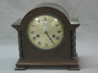 A 1930's striking mantel clock with 5" silvered dial with Roman numerals, contained in an oak arch shaped case with spiral turned columns to the side