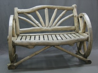 A bleached wooden garden bench, the ends in the form of cart wheels 50"