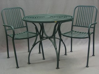A circular green metal garden table 32" together with 4 matching rail back open arm chairs