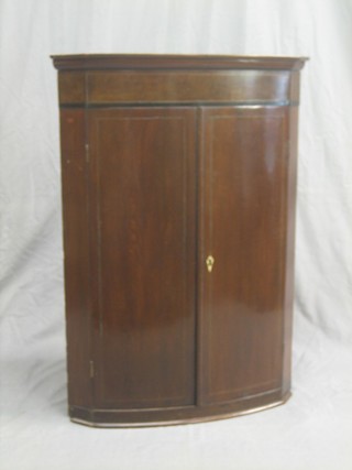 A 19th Century mahogany bow front hanging corner cabinet with moulded cornice, fitted shelves enclosed by panelled doors 26"