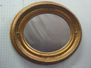 An oval plate wall mirror contained in a decorative gilt frame 32"