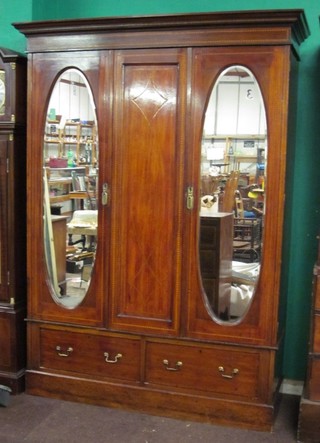 An Edwardian inlaid mahogany double wardrobe with moulded cornice enclosed by panelled doors fitted by oval plate mirrors, the base fitted 2 long drawers, raised on a platform base 58"
