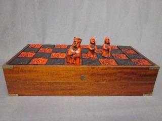 A large wooden folding chessboard table, raised on X framed supports together with resin chess pieces