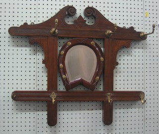 An Edwardian walnut hanging coat rack, fitted brass hooks and having horse shoe shaped bevelled plate mirror to the centre 24"