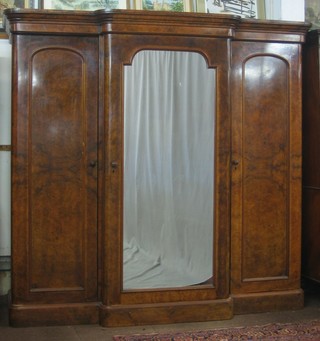 A handsome Victorian figured walnut triple breakfront wardrobe with moulded cornice, the centre section enclosed by a mirror panelled door flanked by cupboards enclosed by arch shaped panelled doors 83"