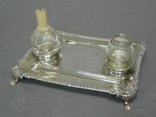 A 19th Century rectangular silver plated ink stand with 2 pen recepticals, gadrooned border and associated glass candlestick and inkwell, raised on hoof panelled feet 9"