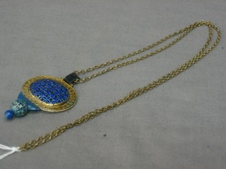 A gilt pierced metal and enamelled pendant hung on a gold chain