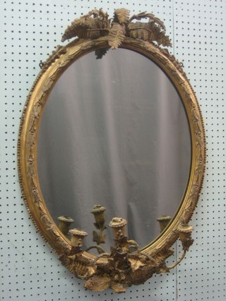 A Regency oval plate wall mirror contained in a decorative gilt frame surmounted by fern leaves, the base fitted 3 candle sconces 25"