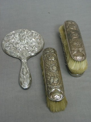 An embossed silver backed hand mirror and 3 embossed silver backed clothes brushes