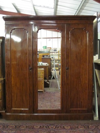 A Victorian mahogany triple wardrobe with moulded cornice, the interior fitted trays above 2 short and 2 long drawers, enclosed by a mirrored panel door, flanked by a pair of cupboards enclosed by panelled doors, raised on a platform base 70"