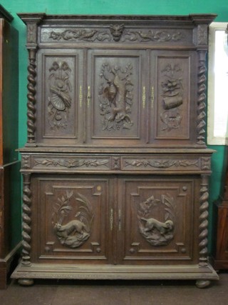 A Victorian carved oak cabinet on cabinet, the upper section fitted 3 cupboards enclosed by carved panelled doors, decorated game trophies, the base fitted 2 long drawers above cupboards, raised on bun feet 54"