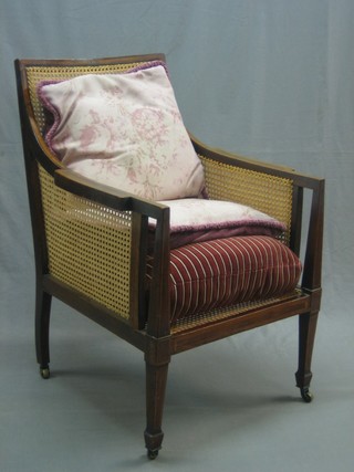 An Edwardian inlaid mahogany single cane bergere library chair, raised on square tapering supports ending in spade feet 