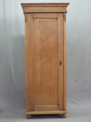 A pine cupboard with moulded cornice, the interior fitted shelves enclosed by panelled doors, raised on bun feet 29"