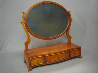 A Georgian style oval plate dressing table mirror contained in a yew frame, the base of serpentine outline with 1 long drawer and 2 short drawers, raised on bracket feet
