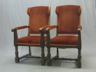 A pair of oak framed open arm chairs, raised on turned and block supports