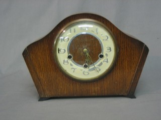 A 1930's chiming mantel clock with silvered chapter ring and Arabic numerals contained in an oak arch shaped case