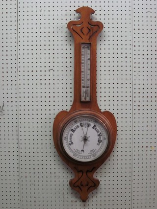 An Art Nouveau aneroid barometer and thermometer with porcelain dial, contained in an oak pierced wheel case