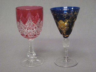 A funnel shaped etched blue glass wine glass together with a Cranberry cut glass wine glass 