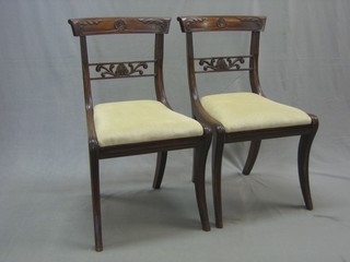 A pair of William IV carved mahogany bar back dining chairs with pierced mid rails and upholstered drop in seats, raised on sabre supports