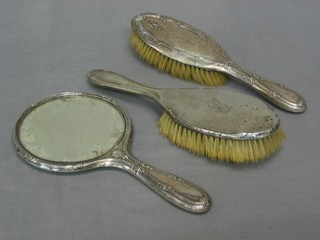 A silver backed hand mirror and 2 silver backed hair brushes