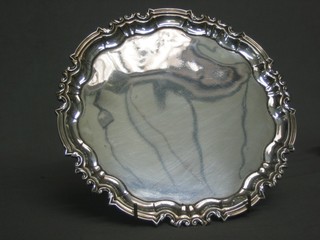An Edwardian style circular silver salver with bracketed border, raised on 4 scrolled feet London 1908, 18 ozs
