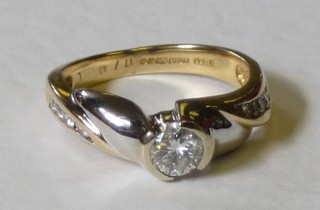 An 18ct two colour gold dress ring set a solitaire diamond and diamonds to the shoulders, approx 0.57ct