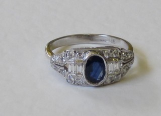 An 18ct white gold dress ring set an oval cut sapphire supported by 4 baguette cut diamonds and surrounded by numerous diamonds